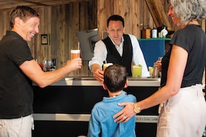 A bar area with wooden walls, a counter, and various bottles.
