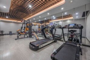 Een sportschool met loopbanden, trainingsfietsen en gewichtstoestellen.