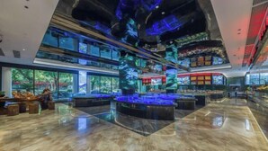 A spacious lobby with a marble floor, a central bar area, and a view of the outdoors through large windows. - Wangfu International Hotel (Yiwu)