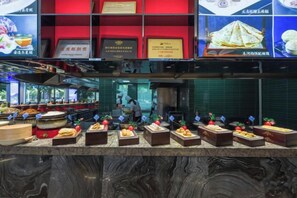 A food display with various dishes, a kitchen area, and a counter with food items. - Wangfu International Hotel (Yiwu)