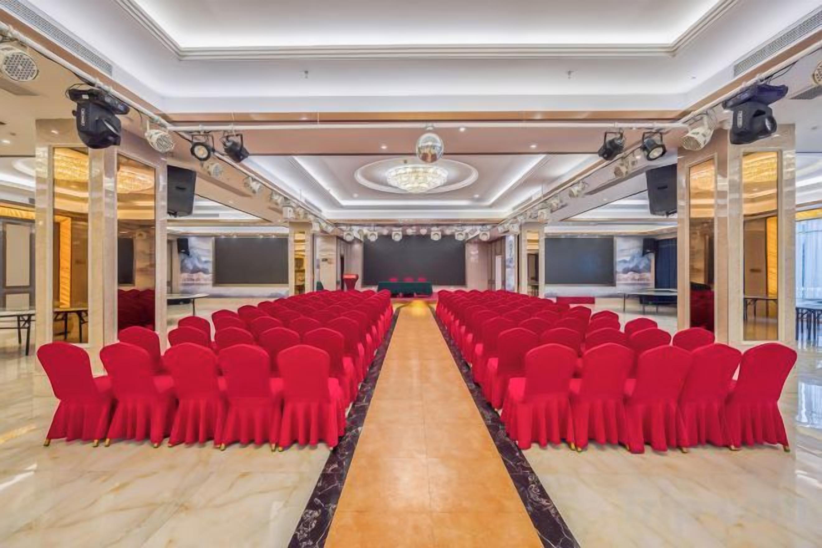 Un salón de conferencias con filas de sillas orientadas hacia un escenario.