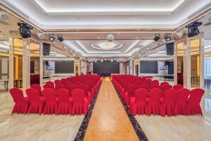 A conference room with rows of chairs facing a stage. - Wangfu International Hotel (Yiwu)