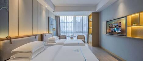 A hotel room with two beds, a TV, a small table, and a large window.