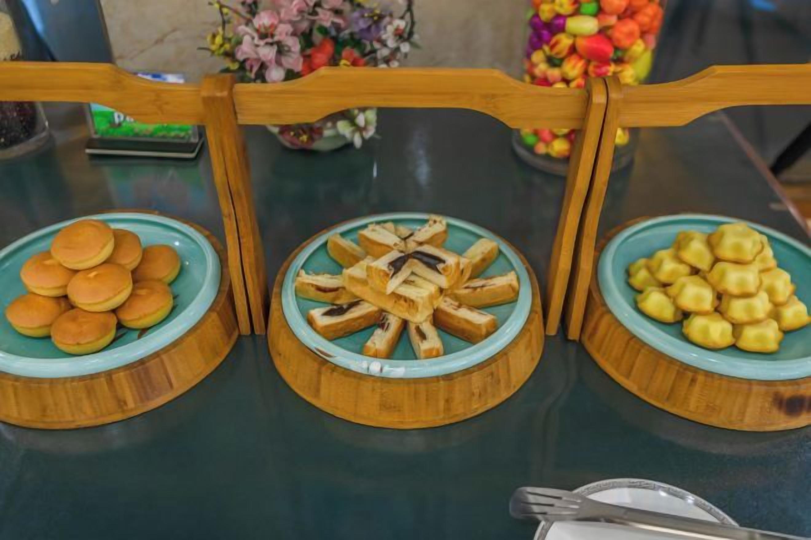 A table with three wooden plates containing food items.