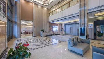 A spacious lobby with a reception desk, seating area, and a large plant.