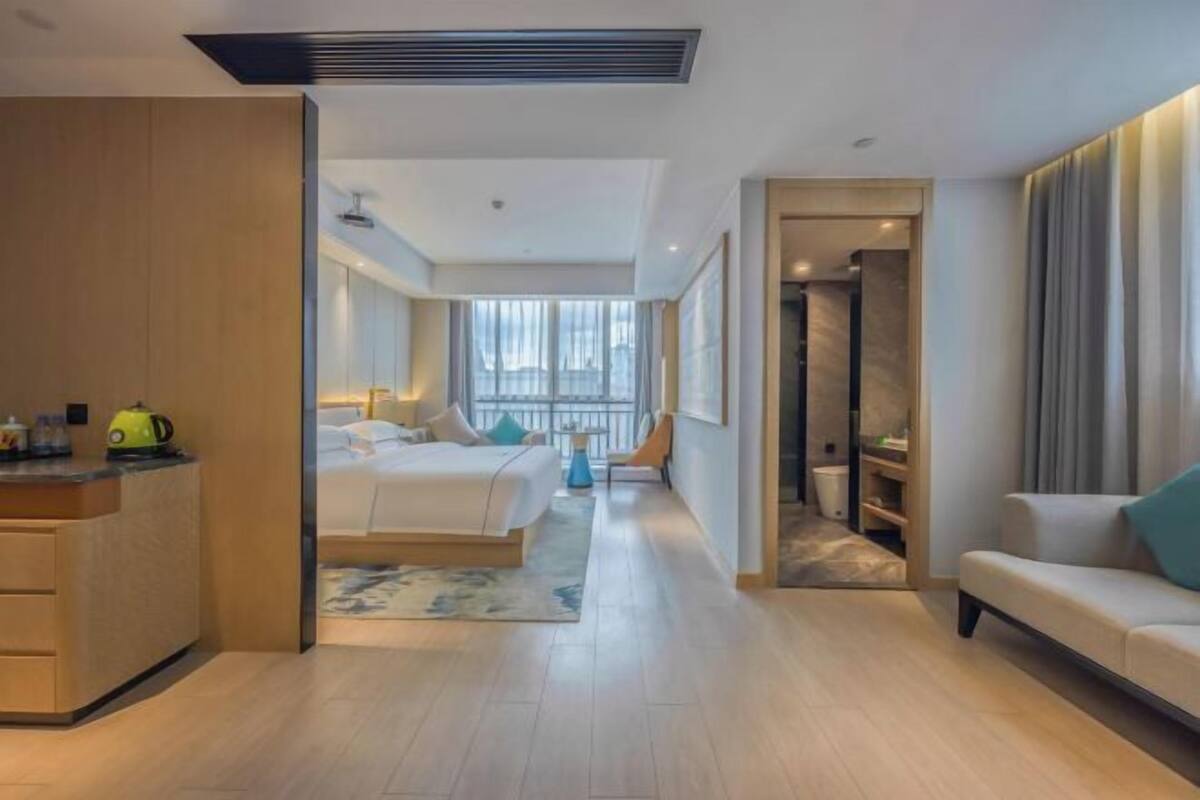 Una habitación de hotel moderna con cama, sofá, escritorio y baño.