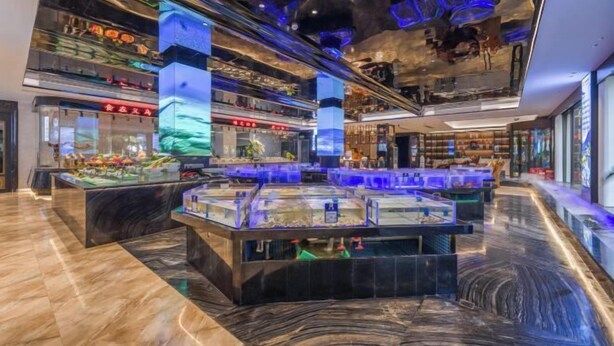 A modern interior with a central aquarium display, glass partitions, and a marble floor. - Wangfu International Hotel (Yiwu)