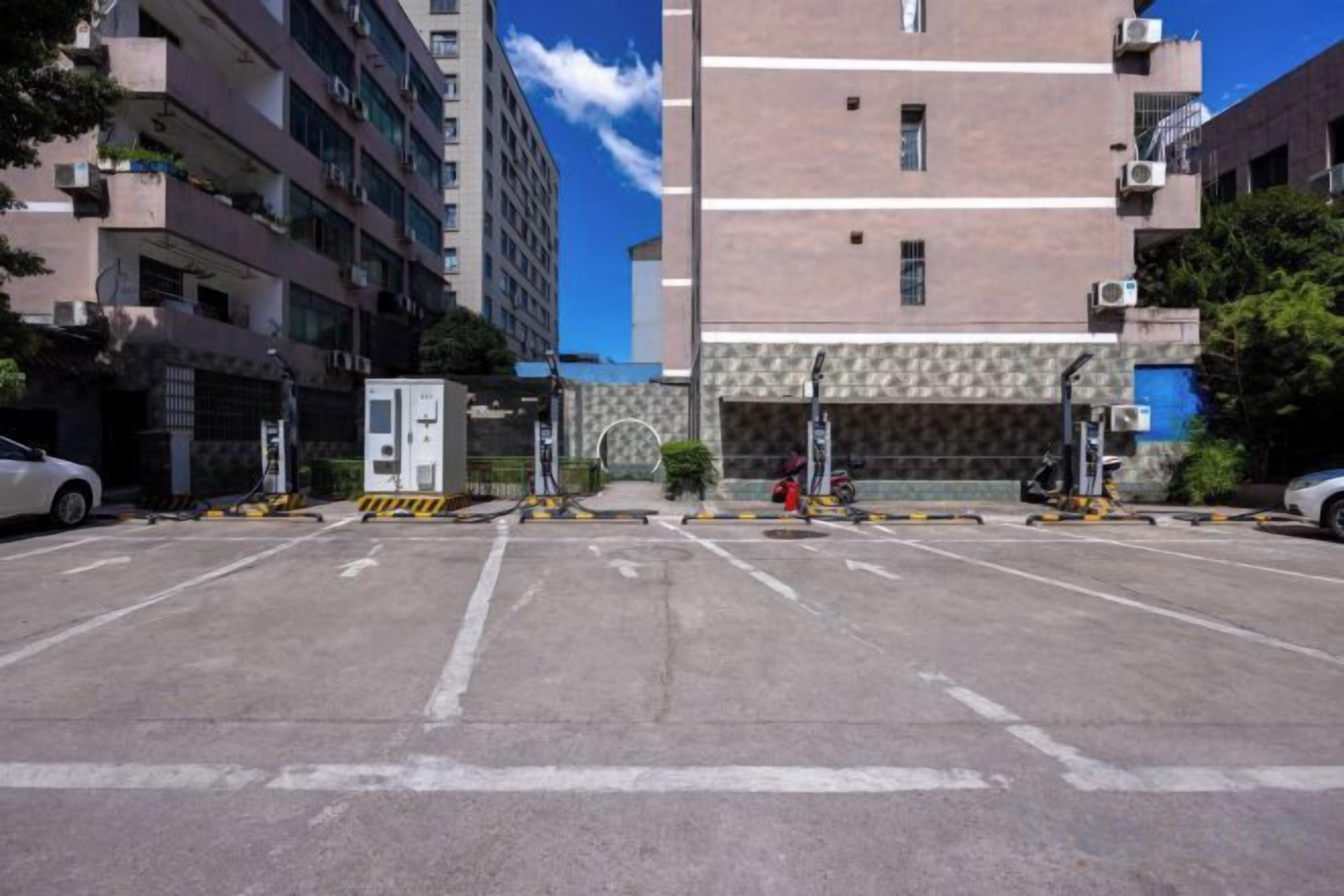 A parking lot with multiple parking spaces, a building entrance, and a clear sky.