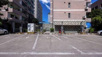 A parking lot with multiple parking spaces, a building entrance, and a clear sky.