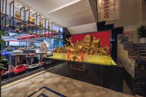 Eine Hotelhalle mit einer großen, goldenen Statue, einer roten Wand und einer modernen Treppe.