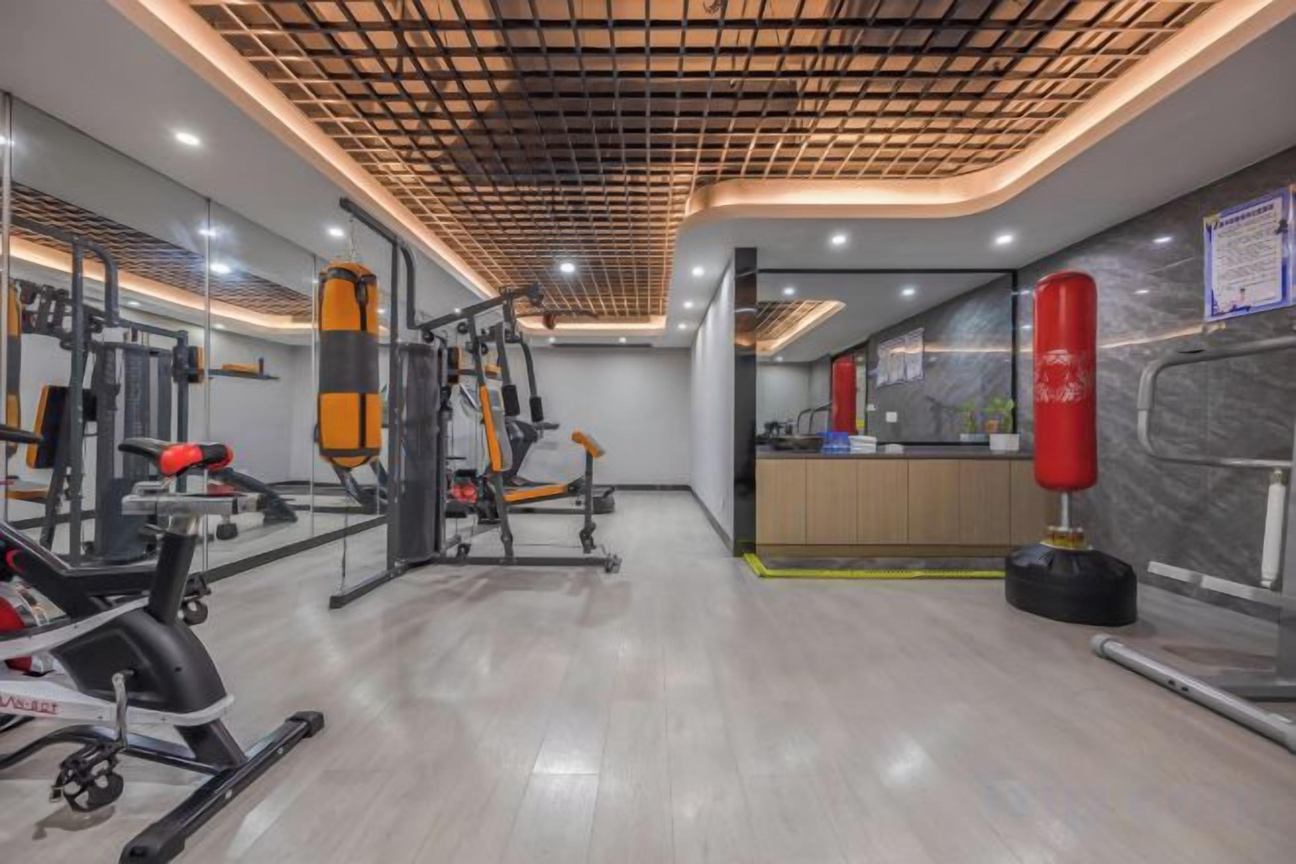 A gym with exercise equipment, a punching bag, and a mirror.