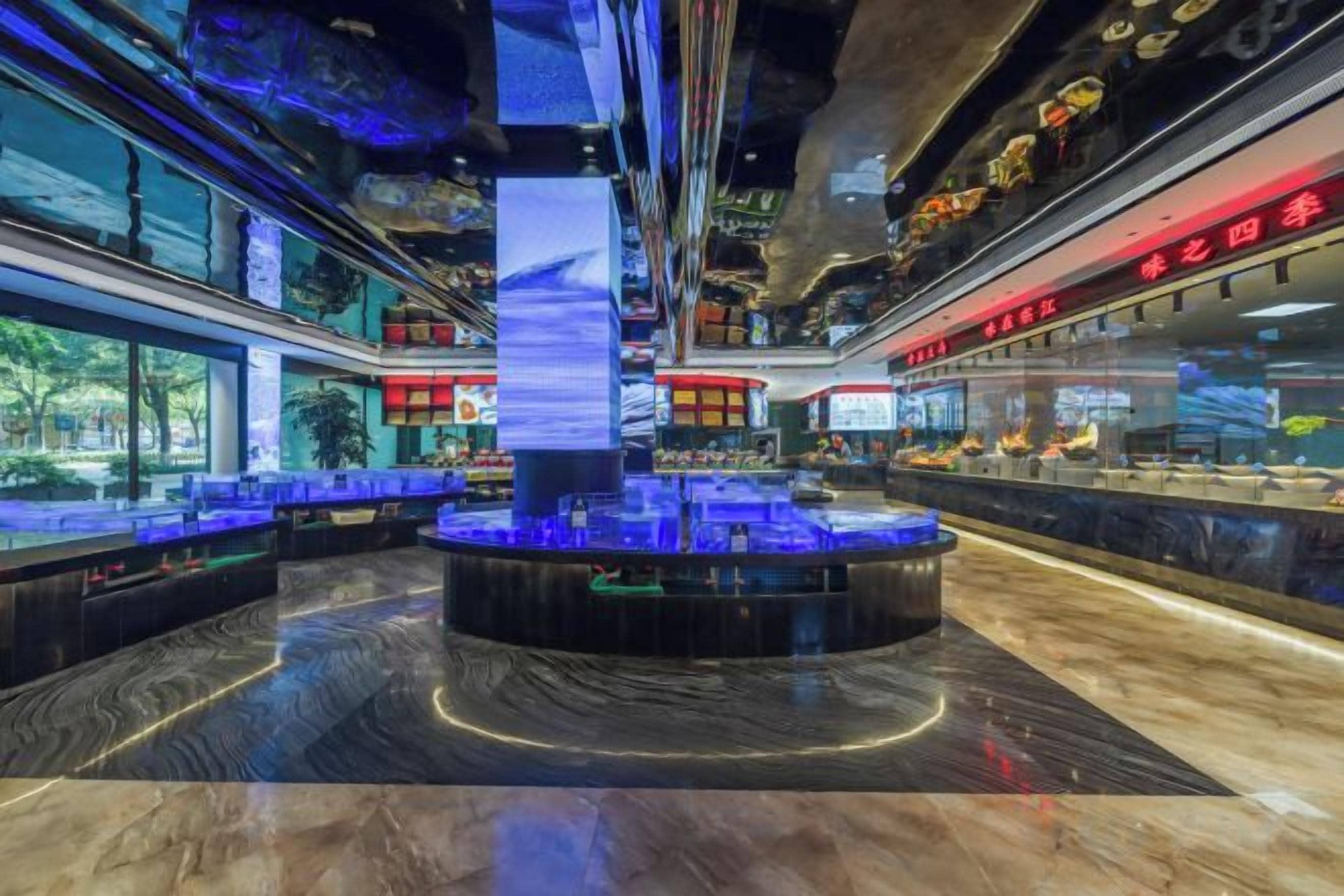 Un intérieur moderne avec un bar circulaire central, des espaces aménagés pour s’asseoir et un grand pilier vertical.