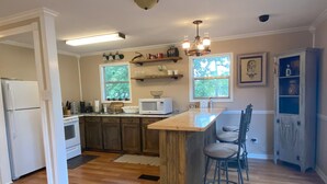 Una cucina con mobili in legno, un frigorifero bianco, un forno a microonde e un'isola con sgabelli da bar.