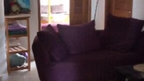 Una sala de estar con un sofá morado, una puerta de madera y un cuadro en la pared.