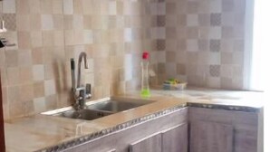 Una cocina con lavamanos, armarios y salpicadero de azulejos.