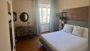 A bedroom with a bed, a desk, a chair, a mirror, and a window with curtains. - Domus Schipa (Naples)
