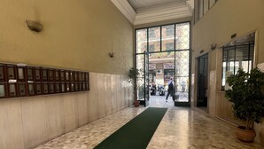 A hallway with a green carpet, tiled floor, and a wall with framed pictures. - Domus Schipa (Naples)