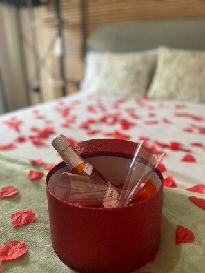 A bed with rose petals and a red cup with a bottle and glass on it. - Domus Schipa (Naples)