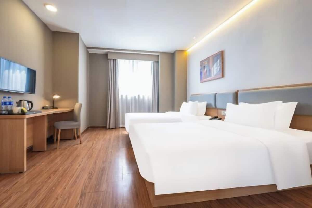 A hotel room with a bed, desk, chair, and a television.