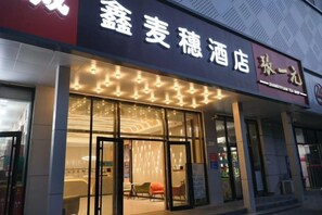 A hotel entrance with a glass facade, a signboard with Chinese characters, and a well-lit interior. - Xin Maisui Hotel (Shijingshan Chaoyang Hospital West Campus) (Beijing)