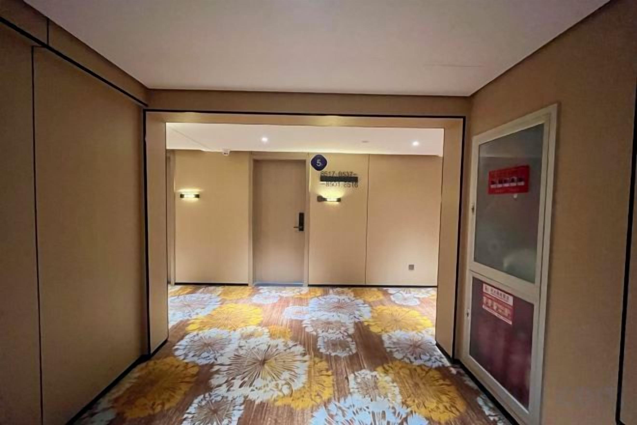 A hotel corridor with a patterned carpet, a reception desk, and a sign indicating the location.