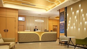 A reception area with a modern design, featuring a reception desk, seating area, and a wall-mounted TV. - Xin Maisui Hotel (Shijingshan Chaoyang Hospital West Campus) (Beijing)