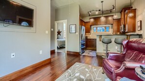 A modern living room with a leather sofa, a dining area with bar stools, and a kitchen with wooden cabinets and stainless steel appliances. - Cozy Heights Hideaway :Pets welcome-Big Frontyard (Houston)