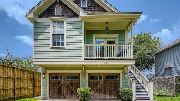 A two-story house with a balcony, a front porch, and a garage. - Cozy Heights Hideaway :Pets welcome-Big Frontyard (Houston)