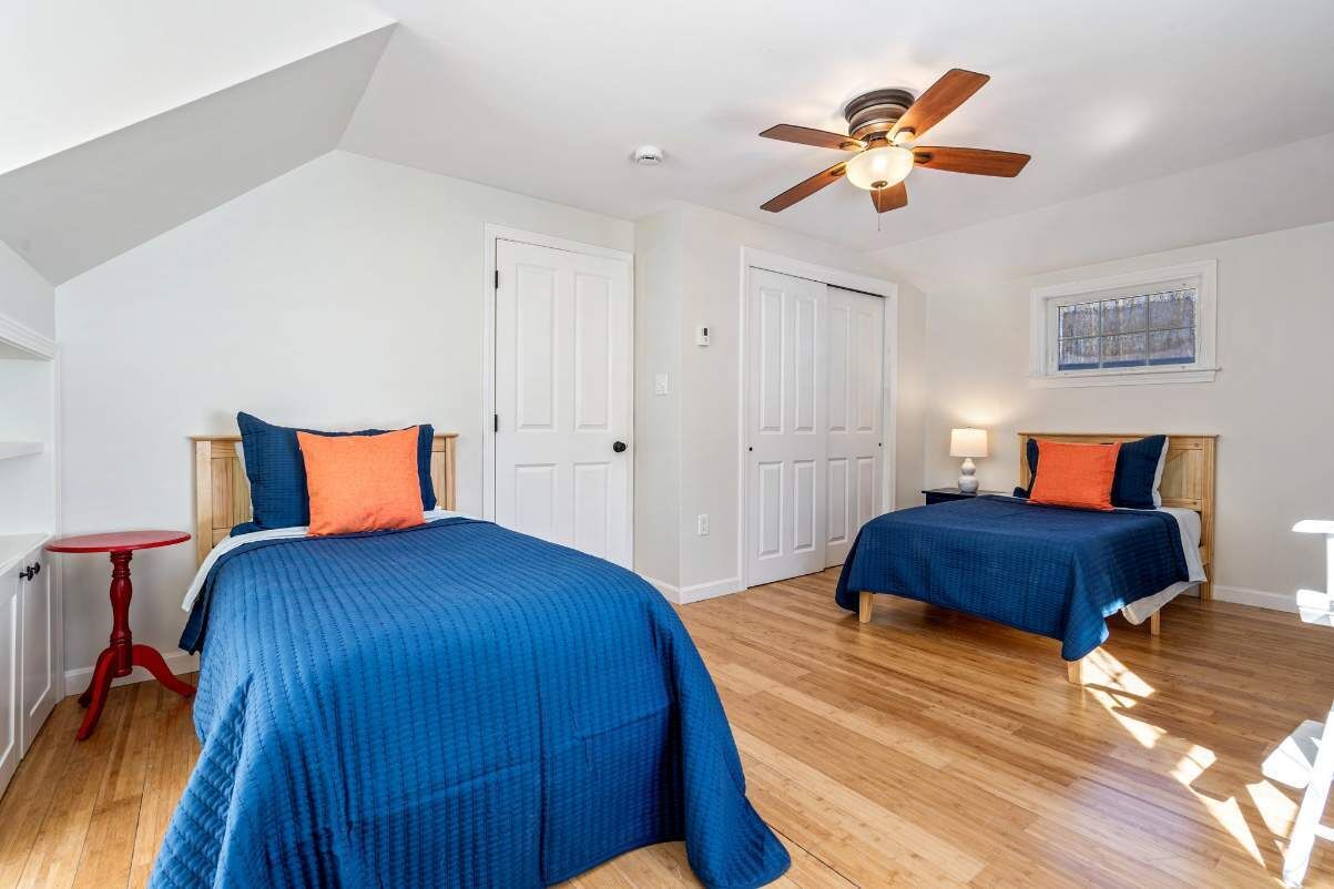 A bedroom with two beds, a ceiling fan, and a window.