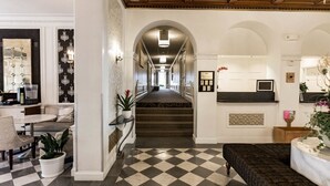 A hotel lobby with a checkered floor, a staircase, a reception desk, and a seating area. - San Diego | City Retreat | Fitness + Sun Deck (San Diego)