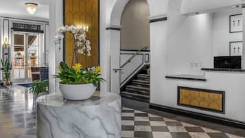 A lobby with a marble column, a staircase, and a reception desk.