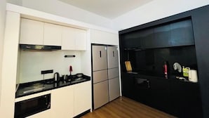 Una cocina compacta con armarios blancos, encimera negra y salpicadero negro.