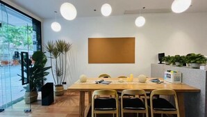 Un comedor moderno con una mesa de madera, cuatro sillas, iluminación colgante y plantas en macetas.