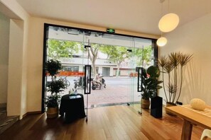 A hotel entrance with a glass door, indoor plants, a wooden floor, and a table with a vase. - Songhua Business Hotel (Shanghai)
