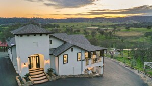 A two-story house with a balcony, a driveway, and a view of the surrounding landscape.