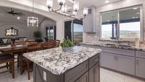 A spacious kitchen with granite countertops, dark cabinetry, and a large window offering a view of the outdoors.