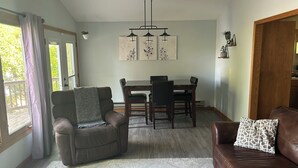 Un coin repas avec une table et des chaises, un canapé en cuir marron et un tapis à motifs.