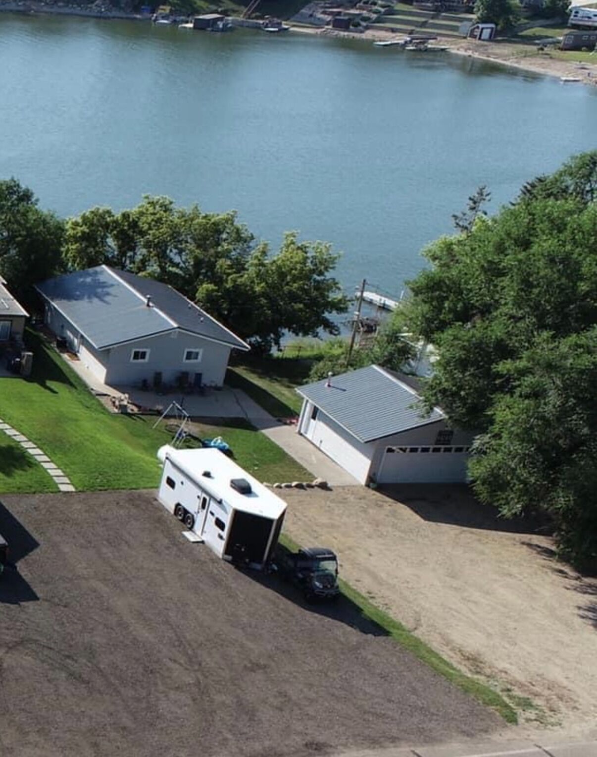 Un quartier résidentiel comprenant des maisons, une caravane et un plan d’eau.