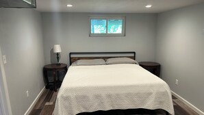 Une chambre à coucher avec un lit, deux tables de chevet, une fenêtre et une lampe.