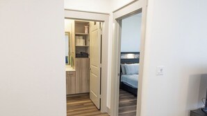 Un couloir au plancher de bois menant à une chambre à coucher avec un lit et une vue sur la mer.