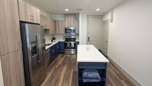 Une cuisine moderne dotée d’appareils électroménagers en acier inoxydable, de meubles en bois et d’un plan de travail blanc.