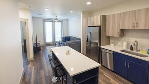 Une cuisine moderne dotée d’un îlot central, d’appareils électroménagers en acier inoxydable et de meubles de rangement bleus.