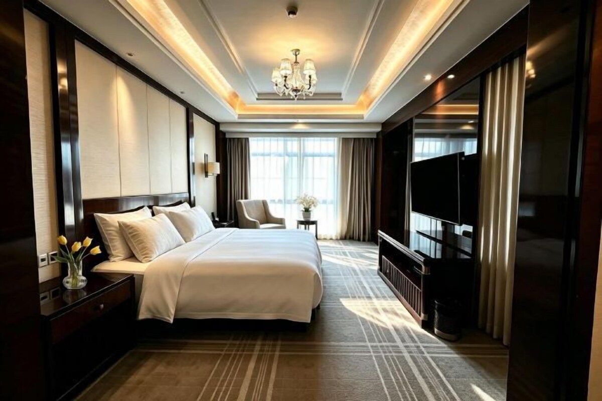 A hotel room with a large bed, a TV, a desk, and a chair.