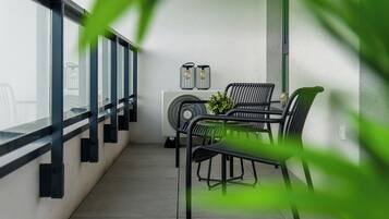 A balcony with a table and chairs, a fan, and two wall-mounted light fixtures.