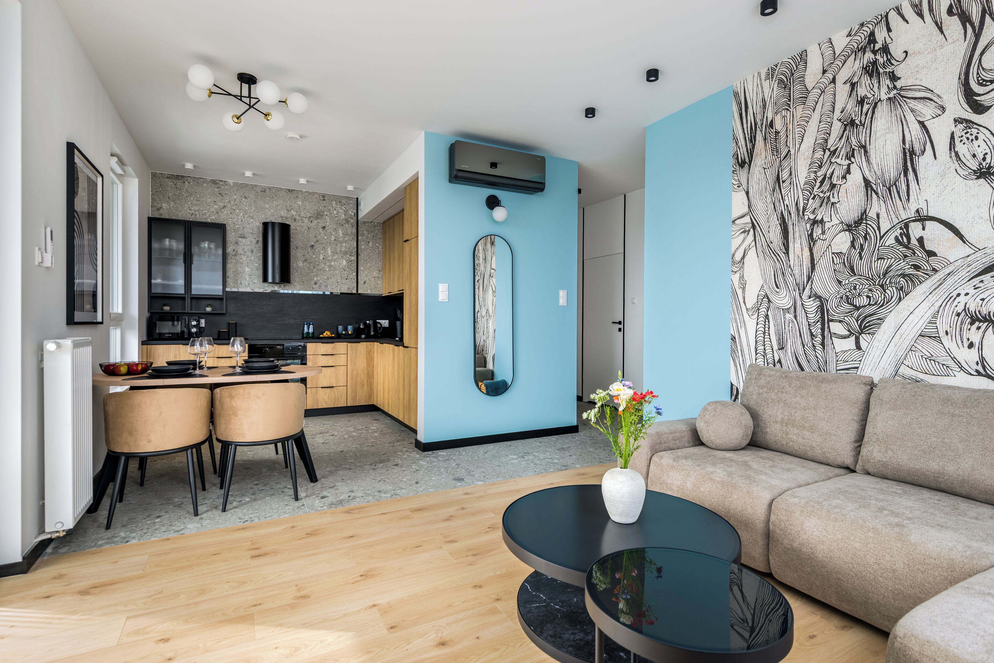 A modern living room with a sofa, a coffee table, and a dining area with chairs and a table.