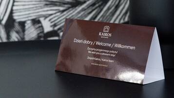 A business card on a table with a black and white abstract wall in the background and a potted plant.