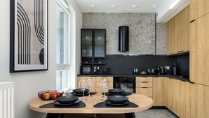 A modern kitchen with a round dining table, black cabinets, and a granite backsplash. - Sky by Kairos Apartments (Katowice)
