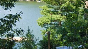 A wooden deck leading to a bench area by a lake, surrounded by trees. - Maine Luxury Home On the Sea (Brunswick)