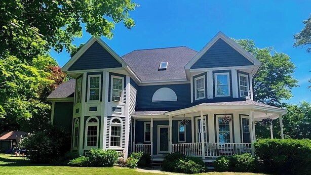 A two-story house with a large porch, multiple windows, and a well-maintained lawn. - Maine Luxury Home On the Sea (Brunswick)