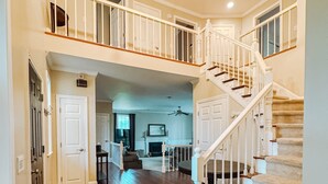 A spacious living area with hardwood floors, a staircase, and a chandelier. - Maine Luxury Home On the Sea (Brunswick)